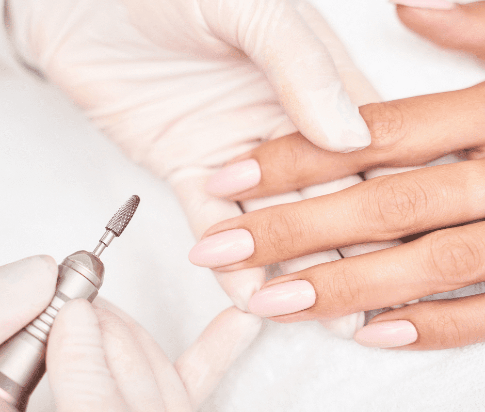 Applying a manicure treatment to fingernails in a salon.